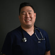 A smiling man wearing a polo shirt and stethoscope, illustrating health and wellness, embodying WeNatal’s focus on prenatal care for men.